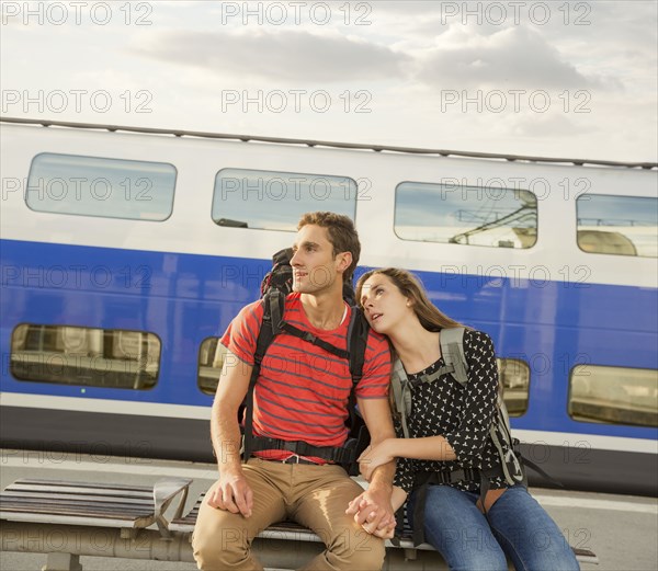 Caucasian couple sitting on bench near train