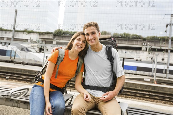 Caucasian couple waiting on bench at train station