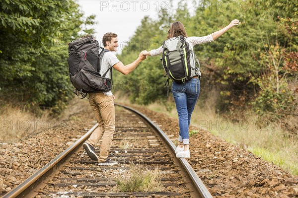 Caucasian couple balancing on train tracks