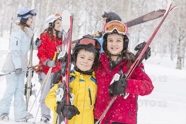 Portrait of smiling Caucasian brother and sister carrying skis