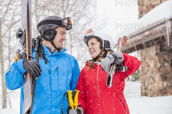 Smiling Caucasian couple carrying skis