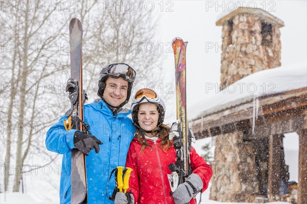 Portrait of smiling Caucasian couple carrying skis