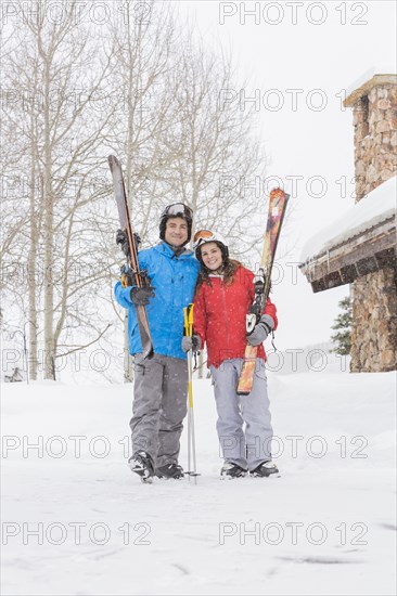 Portrait of smiling Caucasian couple carrying skis
