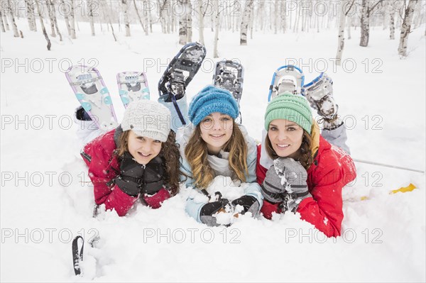 Portrait of smiling Caucasian mother and daughters laying in snow