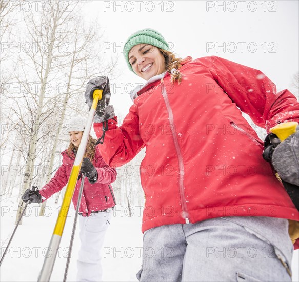 Smiling Caucasian mother and daughter holding ski poles