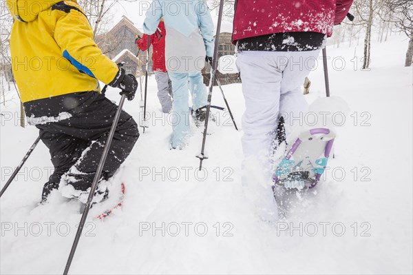 Rear view of Caucasian family snowshoeing