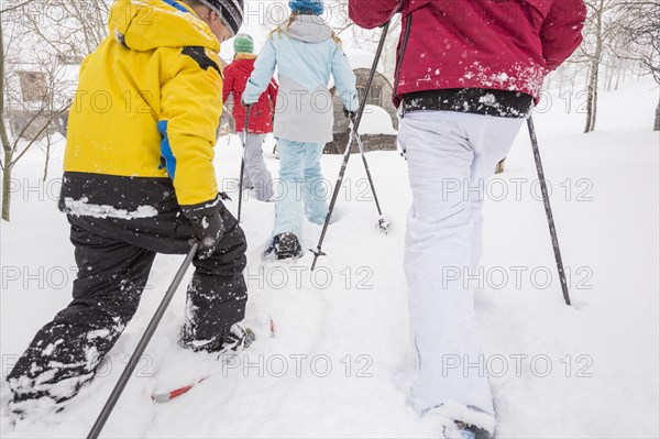 Rear view of Caucasian family snowshoeing