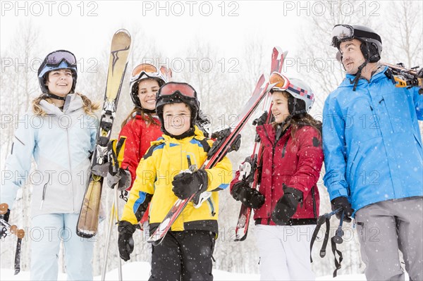 Smiling Caucasian family carrying skis in snow