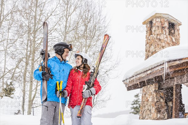 Smiling Caucasian couple holding skis at resort