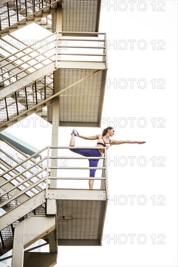 Caucasian woman stretching leg on urban staircase