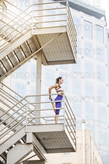 Caucasian woman stretching leg on urban staircase