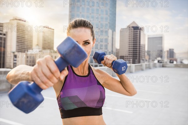 Caucasian woman lifting dumbbells on urban rooftop