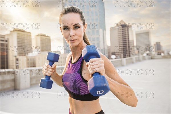 Caucasian woman lifting dumbbells on urban rooftop