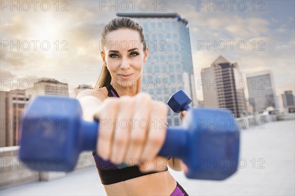 Caucasian woman lifting dumbbells on urban rooftop