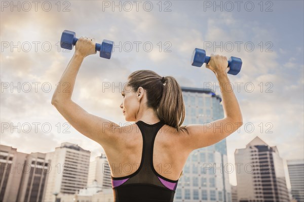 Caucasian woman lifting dumbbells in city