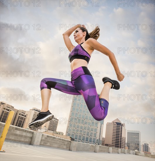 Caucasian woman running and jumping on urban rooftop