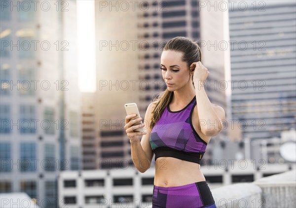 Caucasian woman texting on cell phone on urban rooftop