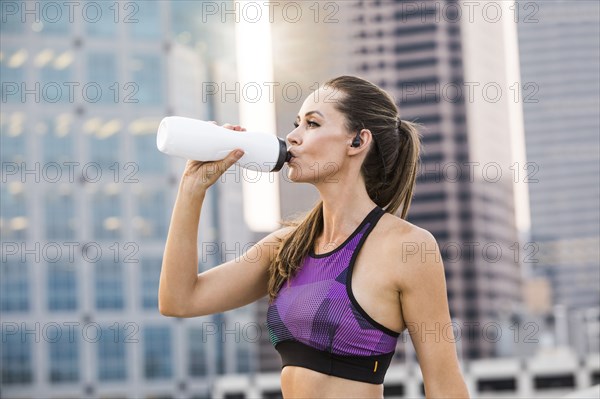 Caucasian woman drinking water in city