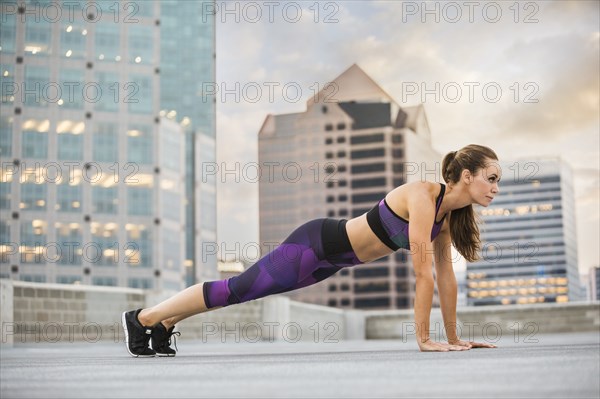 Caucasian woman doing push-ups on urban rooftop