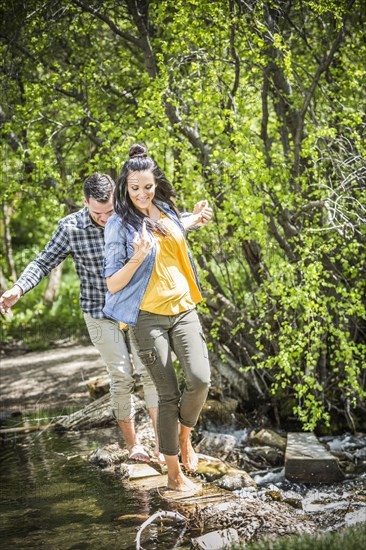 Couple walking on rocks crossing river