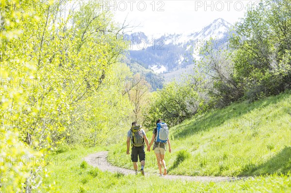 Couple carrying backpacks hiking on path
