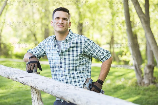 Mixed race man holding drill cleaning on the wooden fence