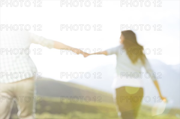 Defocused couple holding hands walking near mountain