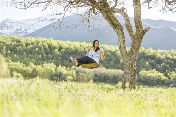 Caucasian woman swinging on tree swing