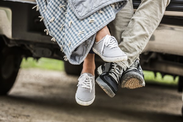 Feet of couple wrapped in blanket sitting on bed of pick-up truck