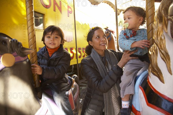 Mother and children enjoying carousel ride