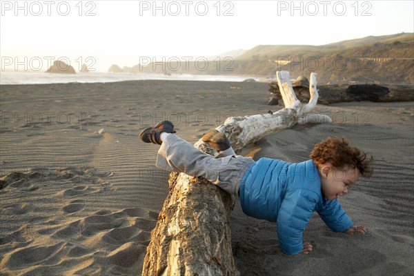 Mixed race boy crawling on beach