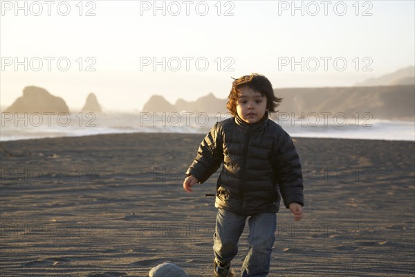 Mixed race boy running on beach