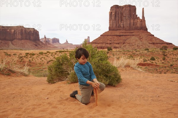 Mixed race boy playing in dirt in Monument Valley