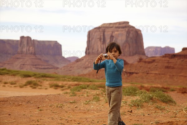 Mixed race boy taking pictures in Monument Valley