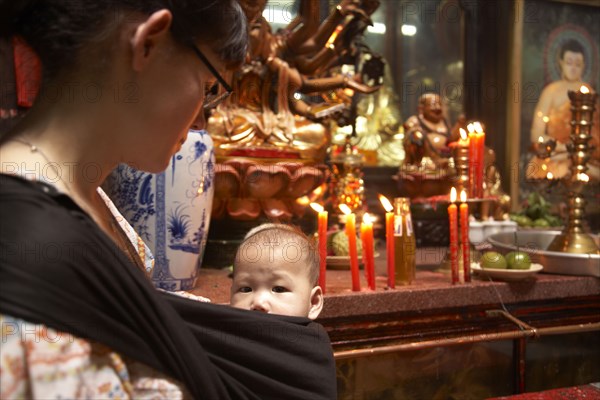 Mother carrying baby in sling in temple