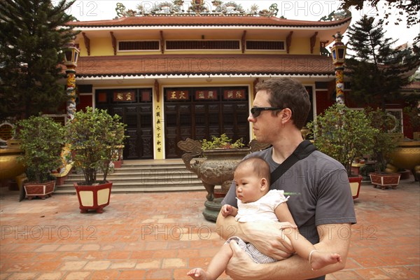 Father carrying baby girl in courtyard