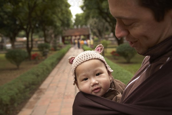 Father carrying baby in sling in park