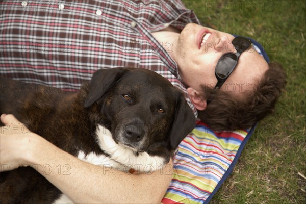 Caucasian man laying in park with dog