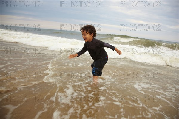 Mixed race boy playing in ocean waves