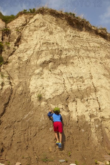 Mixed race boy climbing dirt cliff