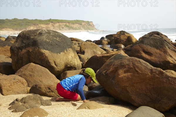 Mixed race boy looking underneath rocks