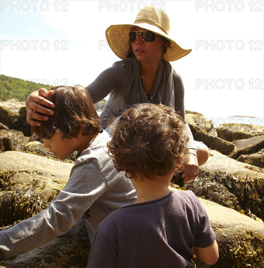 Mother and sons sitting on rocks