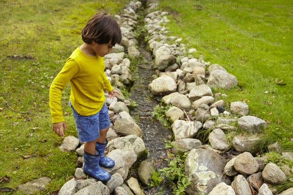 Mixed race boy crossing stream