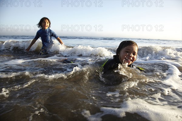 Mixed race boys swimming in ocean