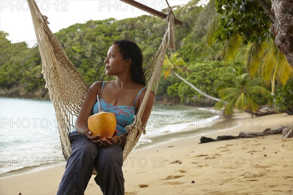 Mixed race woman relaxing in hammock on beach