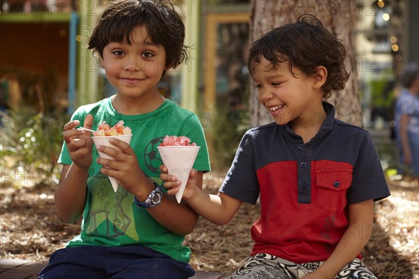 Mixed race boys eating ice cream outdoors