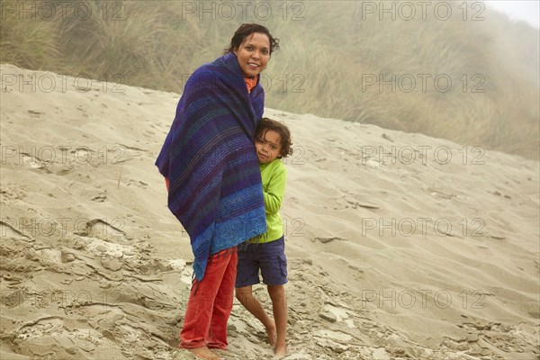 Mixed race mother and son hugging on beach