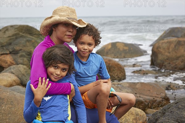 Mother and children hugging on rocky beach