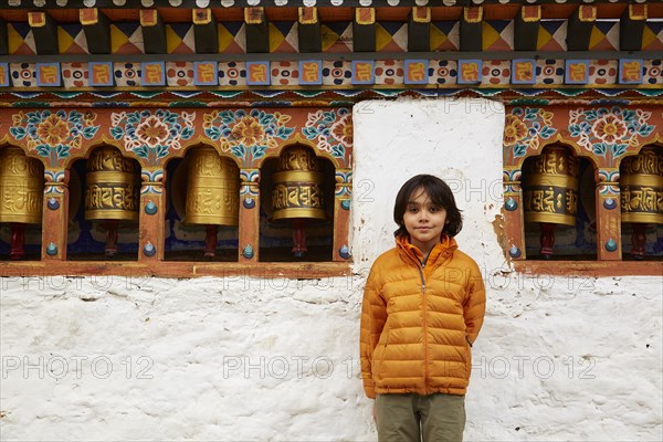 Mixed Race boy standing near prayer wheels