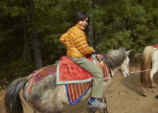 Mixed Race boy riding horse